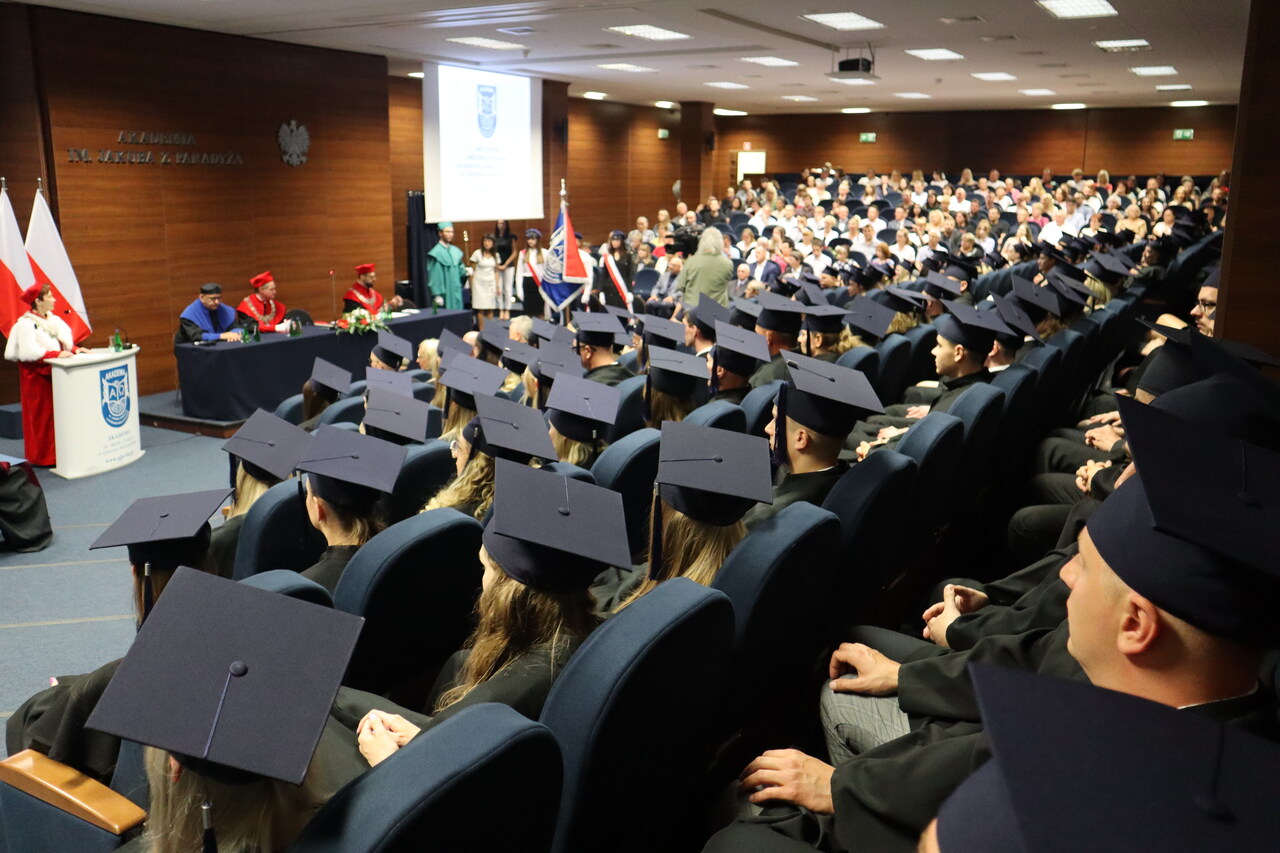 studenci w togach siedzący na auli podczas rozdania dyplomów